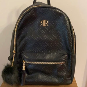 River island svart och guldig väska - Säljer denna superfina svarta och guldiga väskan från river island i England. Den kommer med en pompom och en ”tofs” accessoar. Säljer då den aldrig kommit till användning. Den är i nyskick och har aldrig blivit använd. De sista två bilderna är mina. Skriv privat för fler bilder eller vid intresse☺️ 
