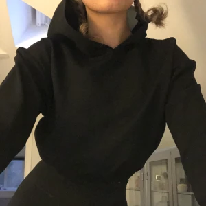 Svart kort hoodie  - Svart oanvänd (lappar kvar) hoodie. Kortare modell med en luva. Jättefin