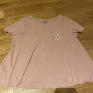 En rosa t shirt med ett a på 