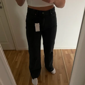 Svarta raka jeans med slitningar - Snygga svarta jeans med hål på knäna. Är oanvända med prislapp kvar och löpta för ca 1 månad. Hög midja och rak passform. Nypris 240
