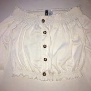 Vit gullig top från H&M - As slt topp från H&M med knappar. Säljes för att den är för liten. Strl: XS. Passar sjukt bra med en flis till. Alla kläder tvättas såklart innan paketet postas! Köp begagnat och billigt för att spara pengar och hjälpa våran fina planet!