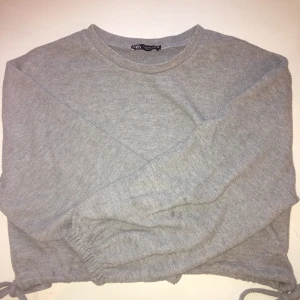 Grå magtröja från Zara - Denna superfina grå tröjan från Zara. Jättemysig och fin! ”Magtröja” eftersom man ser magen om man sträcker upp armarna. Supersöt med rosetter på sidorna! Alla plagg som säljes tvättas såklart innan paketet postas! Size: SX/S