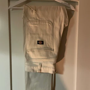 Dickies Garyville Ecru 32x34 - Gräddvita eller ecrufärgade Dickiesbyxor med detaljer liknande arbetsbyxor. Sparsamt använda och inga defekter. Säljer på grund av att de blivit för korta för mig. Priset kan diskuteras.                           Benytterlängd 105cm, beninnerlängd 80cm.                                                                                 Bild 2 är lånad från Zalando.