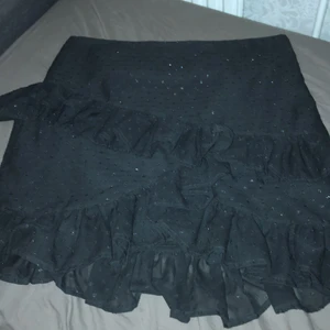 Kjol - Kjol med volanger och glittrar. Är från bik bok och har använts en gång. Är i storlek M