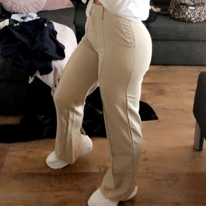 Beigea kostymbyxor - Ett par jättefina kostymbyxor med en liten slit längst ner på båda benen! Dessa kommer från NAKD och är i storlek 34! Kontakta vid fler bilder och frågor💞