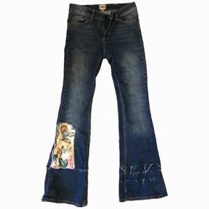 bootcut jeans med fransade trådar på ena benet, tyglapp i andra. sitter under naveln (low waist) och är tajt vid låren. storlek 26 - liten storlek. frakten kan variera!