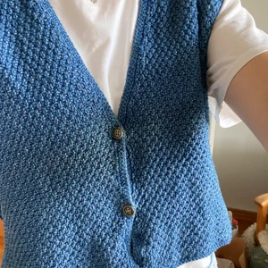 Blå väst med fina detaljer - Blå stickad väst med fina detaljer köpt second hand. Den har fina knappar fram och ett band bak som man kan ta av.