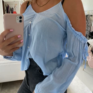 Skjorta utan axlar - Supersöt blå vit randig skjorta utan axlar med axelband man kan spänna åt. Köparen står för frakten på 24kr.