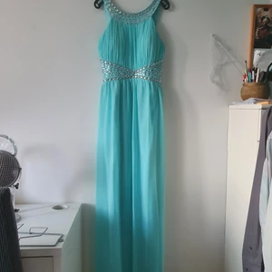 Festklänning  - Ljusblå/turkos fest/balklänning som används endast en gång. Jättefint skick. Köptes för ca 1500 så säljes för halva priset. Finns även en matchande sjal