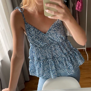 Blommig topp - Säljer denna jättefina blommiga volangtoppen då den inte kommer till användning. Har används en gång och är därmed i fint skick. Säljer för 55 kr + frakt. Obs köparen står för frakten. 