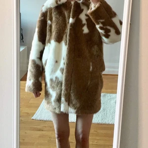 Pälsjacka - Pälsjacka (fejkpäls) i brunvitt komönster. Nätt och rymlig. Djupa fickor och tryckknappar. Knappt använd! 