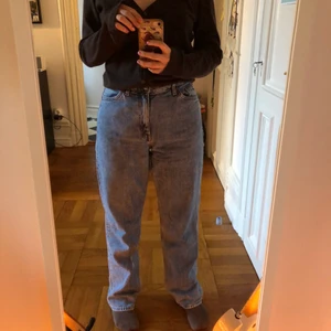 Monki Taiki jeans strl 26 - Högmidjade jeans från Monki i modell Taiki strl 26. Sitter bra på mig som är 162 cm men lite långa i benen, de faller ner över fötterna. 