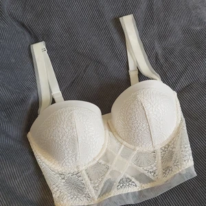 Korsettopp calvin klein - Sååå snygg korsettopp/balconettopp från Calvin Klein. Är i en gräddvit färg men fin spets och mesh över. Är vadderad med minimal push-up och har avtagbara band. Är i storlek 70D/S. Går lika bra att använda som bh eller topp! Fri frakt