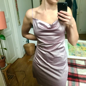 Klänning i rosa/ljuslila satin - Klänning i satin i ljus rosa som går mot violett/ljuslila. Nyskick, använd ett par ggr men är tyvärr för stor för mig 💔 Står M på lappen och är nog rätt tts jag har 34/36 i toppar och 38/40 i byxor). Justerbara axelband och cowl neck!