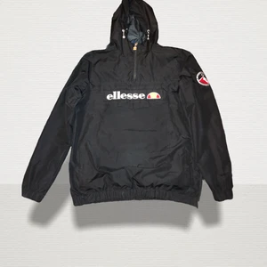 Ellesse- vindjacka  - Material  Material: 100% polyester Foder: 100% polyester  Produktionsinfermation  Krage: Kapuschong med dragsko Förslutning: Dragkedja Fickor: Fickor med lock Detalj huva: Kapuschong med dragsko Detaljer: Istoppsfickor, midjeresår  Storlek: M, 38   Kan fraktas men köparen står för frakt! 