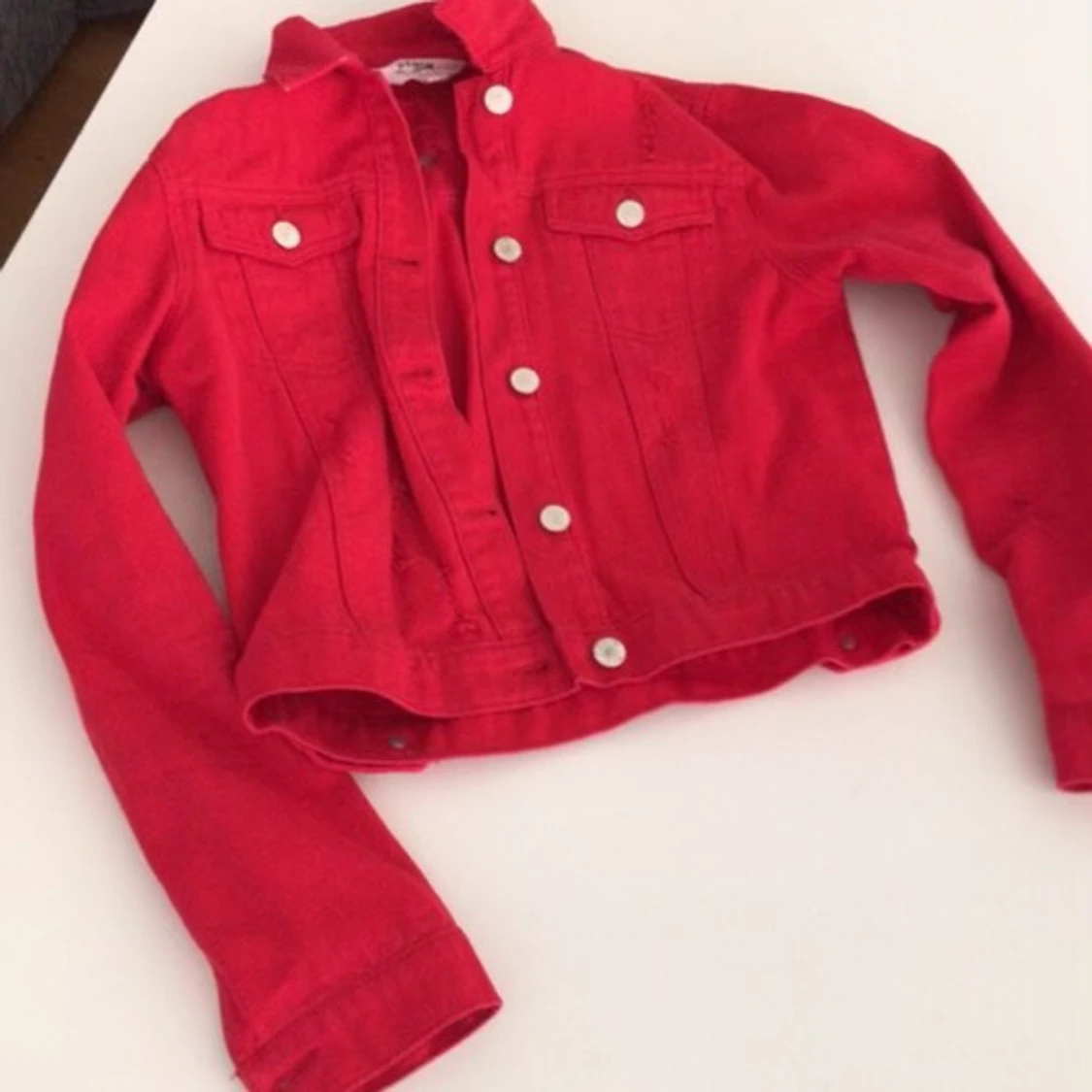 Röd jeansjacka med slitningar