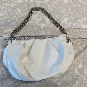 Vit väska med silvrig kedja  - Jätte fin liten väska med silvrig kedja. Vet inte märket. Men använd 1 gång, ny skick 💛