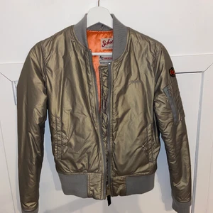 Militärgrön bomberjacka från Schott - Säljer för 999 INKLUSIVE FRAKT!!! PRIS KAN DISKUTERAS! Riktigt cool bomberjacka i en slags glansig militärgrön färg och som även har en orange färg på insidan. Den är varm och riktigt fet till en snygg outfit!!!! Nypris är 1900 och fick i present, använd 1 gång och är verkligen som helt ny🤩🤩🤩 