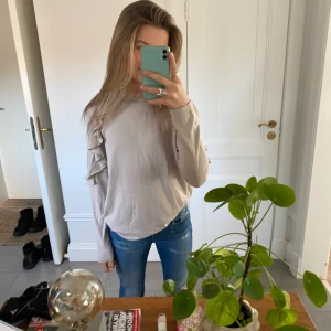 Beige tröja i såå skjönt material! - Säljer min beiga tröja som har lite volanger på armarna! Så sött till en kjol eller bara ett par jeans🥰  Nypris: 220kr, säljer för 120kr! Använd två gånger☺️ I fint skick!! Köparen står för frakt❤️