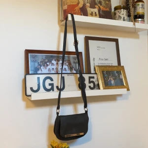 Axelremsväska  - En svart liten axelremsväska som söker nytt hem och en ny ägare. Super gullig men inte riktigt min stil så säljer den ny vidare. 