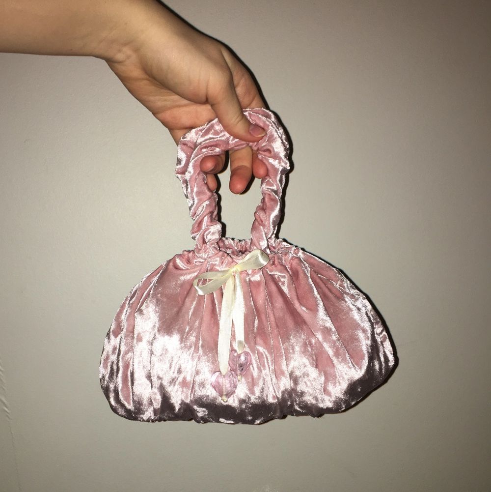 Supersöt liten handväska i återanvänt velourtyg. Väskan är hemmasydd. Handtagen är lite elastiska såsom scrunchies och väskan försluts med ett satinband med hjärtan av glas. Väskan är rymlig och anpassar formen efter innehållet. Önskas mer information ov väskan är du välkommen att kontakta mig. . Väskor.