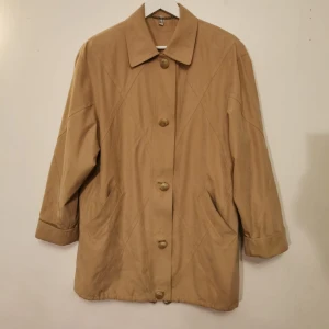 Beige kappa - Stlk 40 Fickor fram, innerficka, fodrad, axelvaddar. Fina applikationer.