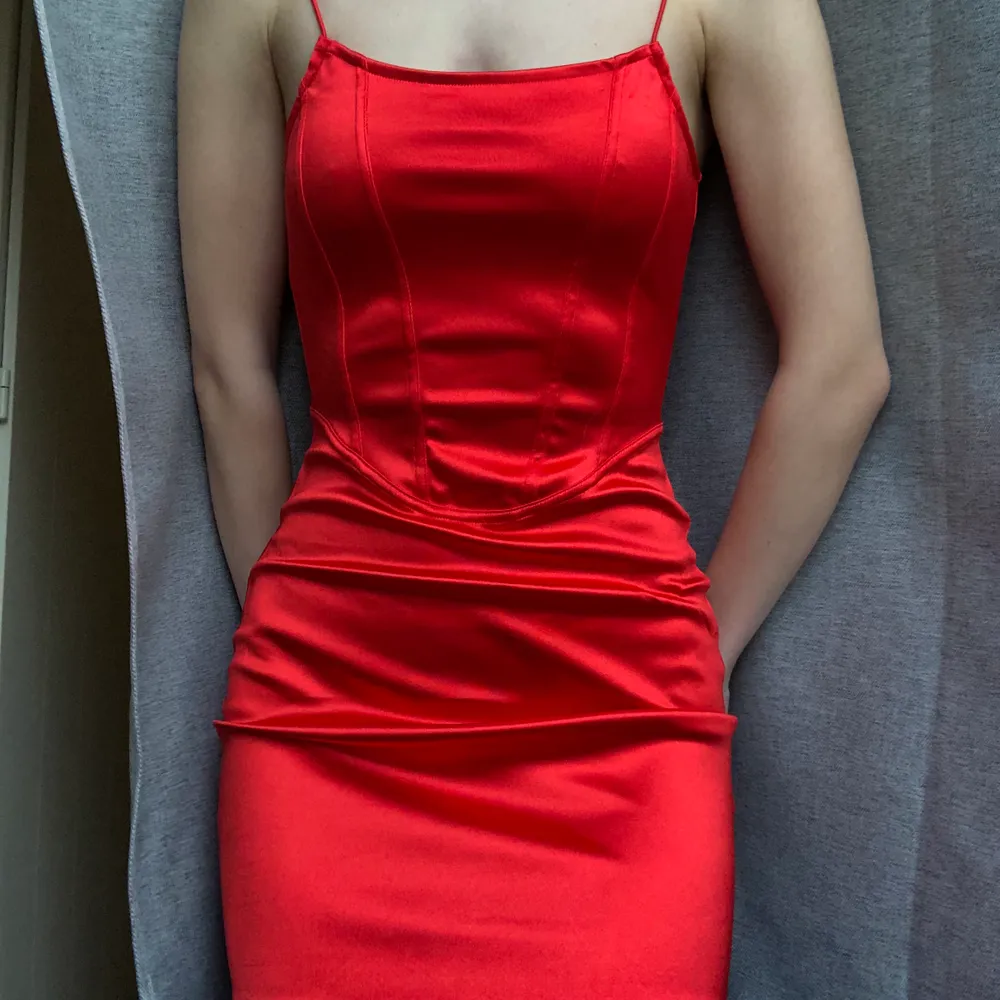 En klänning i röd glänsande satin med korsett detaljer. Kort och tight form. Storlek XS. Från H&M. Helt oanvänd! Leverans 62 kr eller mötas i Malmö. #detaljer #hm #röd #satin #klänning #korsett. Klänningar.