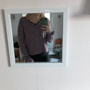 Stickad tröja  - Säljer denna ”lila” tunna stickade tröja från Vero Moda i storlek M, med söta detaljer, rosett vid ärmarna och lite spets vid v-ringningen. Näst intill ny, använd fåtal gånger.