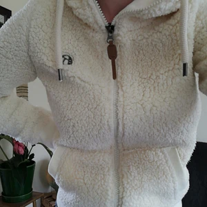 Teddy jacka från Kazane strl. M - Unik, vit teddy jacka från skejtmärket Kazane köpt i Amsterdam. Finns inte i Sverige. Tajt passform med två fickor framtill och dragkedja och luva. 