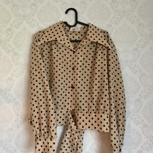 Retro prickig blus - Supersnygg blus i en retrostil! Försluts med knappar och ett knyte längst ner. Storlek 44 men passar mig som har 38. Tror det är en gammal storlek. 