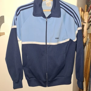 Adidas tröja med dragkedja , fickor. Mörk/ljusblå  - Blå adidas sportjacka med dragkedja.  Det står storlek 174, har ingen aning om vad det motsvarar.  Jag skulle säga gränsfall mellan medium och large. 
