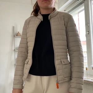 Dunjacka  - Beige lätt dunjacka från save the duck. Med dragkedja och två fickor med knappar. (Ordinarie pris 1600kr) Köparen står för frakten!!