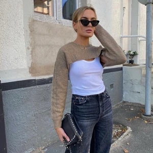 Croppad topp - Super trendig croppad stickad tröja som ”sitter ihop” med ett vitt ribbstickat linne!🤍 Väldigt unik och cool topp som jag tyvärr aldrig använt och därför nu säljer i ny skick. Storlek S men då det är stretchigt material skulle jag säga att den passar xs-m