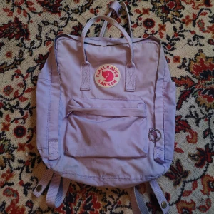 Fjällräven kånken - pastell / pastellila ❤️ - Rätt så fin. Dock har den en del smuts på sig, brukar gå få bort i tvätten.Ihopsydd på ett ställe, inget som syns när man har den på, och inte så värst mycket annars heller. Undertill finns några småhål i den. Storleken är den "vanliga".