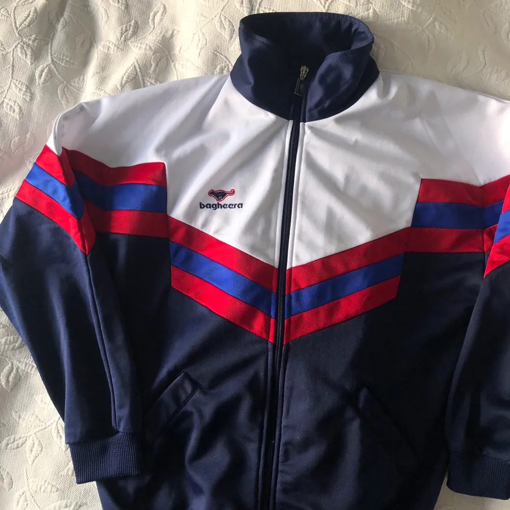 Supercool 80-talsinspirerad track hoodie. Jättebra skick förutom en liten fläck på baksidan (syns knappt för den är så liten, 2a bilden). Den är i barnstorlek men väldigt boxy och därför passar den mig som kan ha Xs/s väldigt bra. Frakten är 66kr 🤎❤️. Tröjor & Koftor.