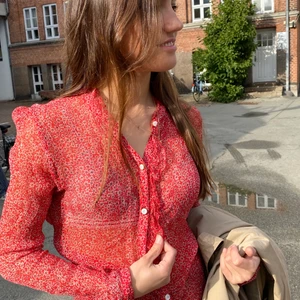 Rød blomstret skjorte - Rød småblomstret skjorte med mega fine detaljer. Let gennemsigtig. Flæser ned langs knaplukningen. Fineste perlemors knapper med guld detaljer 