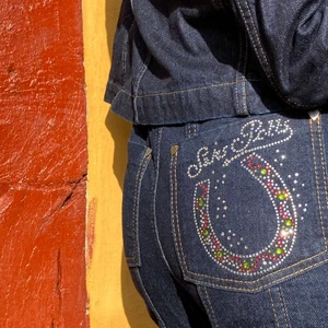Saks Potts jeans med glimmer mås - Saks Potts jeans med glimmer på måsen. Fine deltager med SP logo og hjerte knapper. Højtaljede og lille i størrelsen. Jeg har str. 2 på ca. S/36