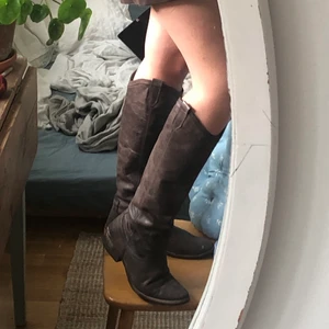 Cowboyboots bruna  - Italienska höga cowboyboots, nyligen inlämnade hos skomakaren för ny vibramsula och klack. Stl 39 men mycket mjukt skinn så kan säkert passa flera storlekar! Speciellt fina iom att de är så sköna och går upp t knäet.