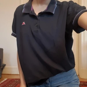 Mörkblå piké - Mörkblå piké från kappa med ljusblå och lila ränder på kragen och ärmarma. Bra skick! 