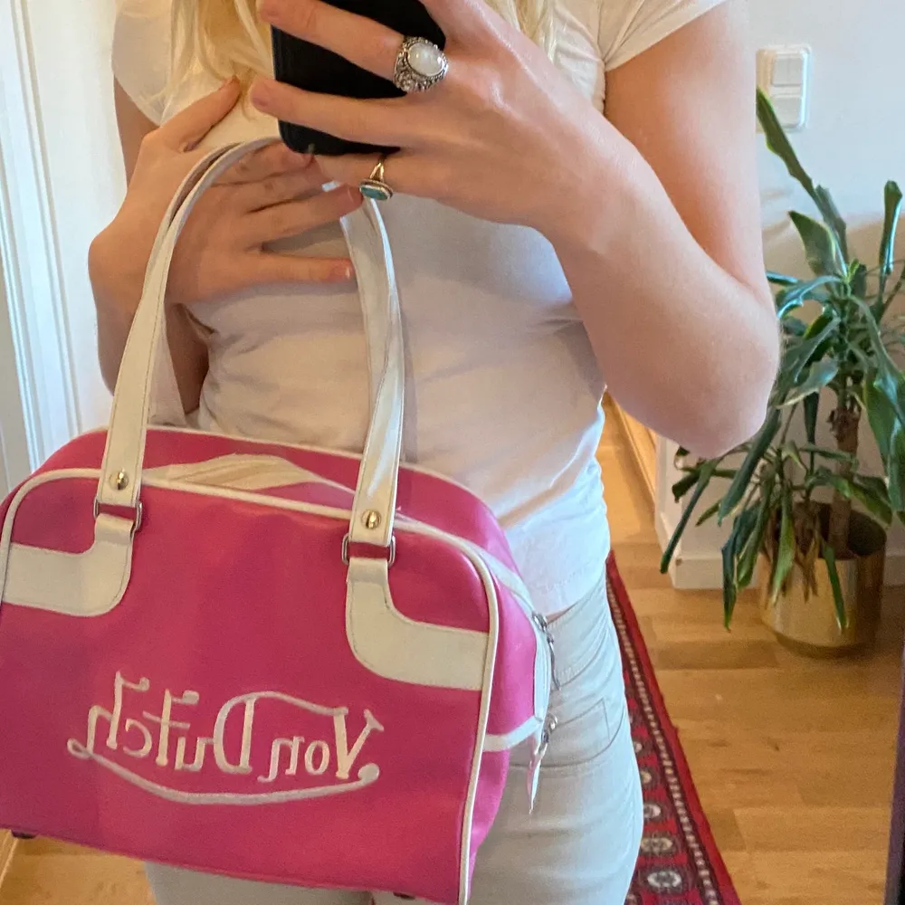 Säljer min underbart fina rosa von dutch väska som är extremt y2k!! Den är använd men i bra skick, det som skulle vara isf är att den skiftar lite från det vita på dragkedjan(kan skicka fler bilder)!! Fraktar men köparen står för frakt💕💕. Väskor.