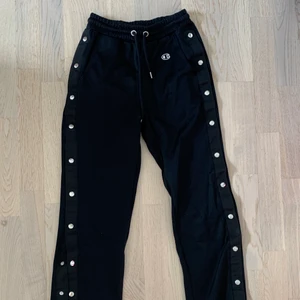 TRACKPANTS CHAMPION - Svarta trackpants från Champion i storlek XS, med öppningsbara knappar, man kan alltså skapa sin egna slits. På mig som är 160 går dem precis till foten. Köpta för 800kr på Weekday och endast använts få gånger. Köpare betalar frakt: 57 kr💌