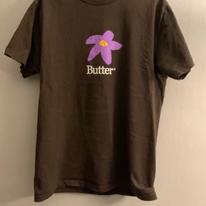 Butter T-shirt strl M - Brun Butter T-shirt med lila blommor fram och bak i strl M lite liten i storleken så passar S också väldigt bra skick köpt för 350 på caliroots
