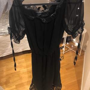 Svart offshoulder-klänning med volanger från NAKD, storlek 38. Helt oanvänd då den inte kommit till användning. Köparen står för eventuell fraktkostnad💕 