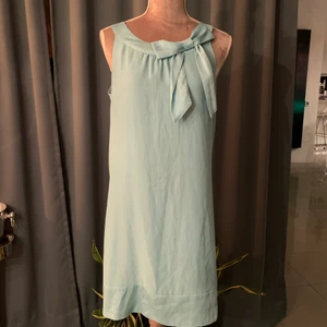 Sommarklänning med rosett fram - Kort sommarklänning i ljusblått silke, ingen stretch. Bra skick!  