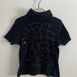 Topp med paljetter - Snygg topp med polo och diskreta paljetter på framsidan. 