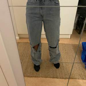 Jeans från Boohoo i storlek 36. Jeansen har stora hål och slitningar nere vit byxbenet. 