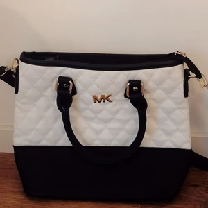 MK handväska - Fin handväska i mellanstorlek med både handtag och axelband. Den är troligtvis inte äkta Michael Kors, men materialet är ändå mjukt och inte plastikt trots att den inte är gjord i äkta läder. Väskan är sparsamt använd, så i gott skick utan repor eller dyl.