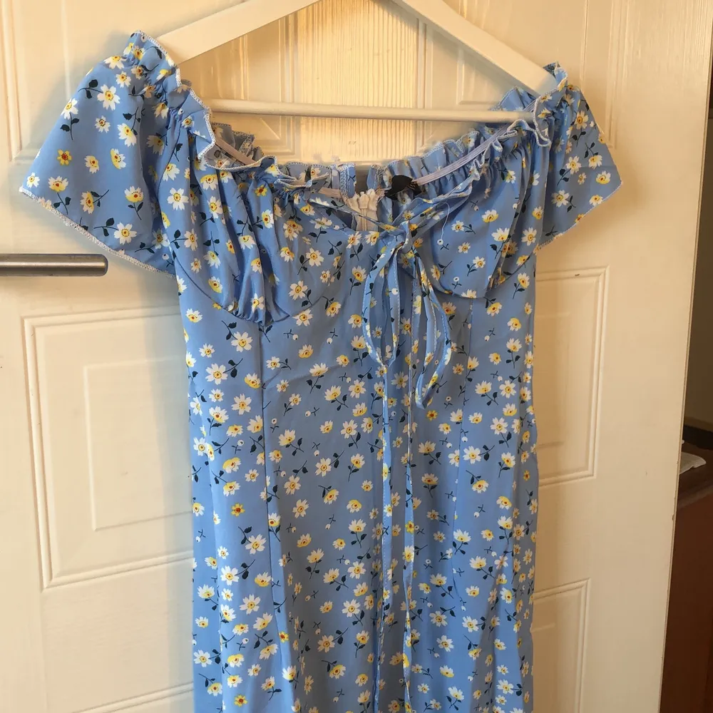 en blå sommar klänning med gula blommor som är helt oanvänd. Jag kan Sicka den men ni får stå för frakten (50kr frakt) sammanlagda pris med frakt 250kr. Klänningar.