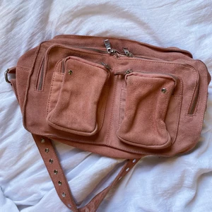 Nunoo väska - Säljer min stora Nunoo väska i en jättefin rosa färg för att jag inte fått användning för den. Jättefint skick förutom att den har några fläckar på undersidan av tidigare ägare (se sista bilden). Jag har inte försökt ta bort dem men går antagligen lätt bort i tvättmaskin. Syns inte när man bär väskan då de är på undersidan🌈❤️💗