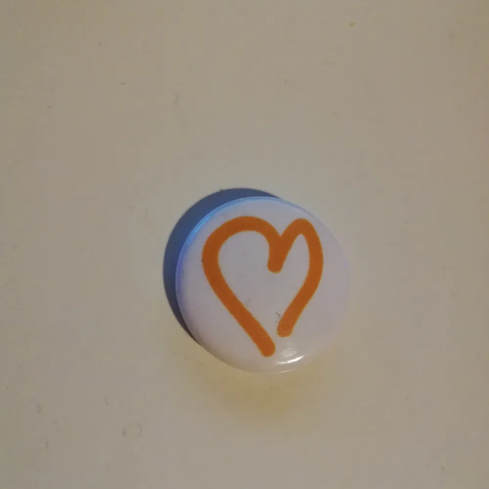 En pin med ett orange hjärta på. . Övrigt.